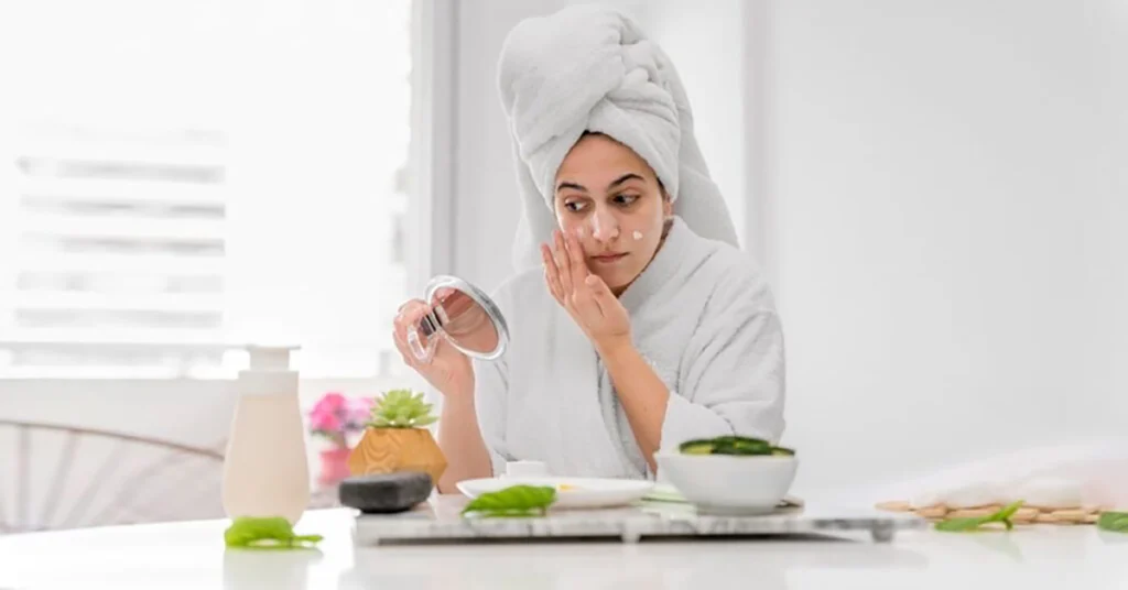  A woman applying face cream during her relaxing skincare self-care routines.