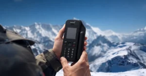 BSNL satellite phone held in hand in a snowy mountain landscape, showing reliable communication in remote locations.